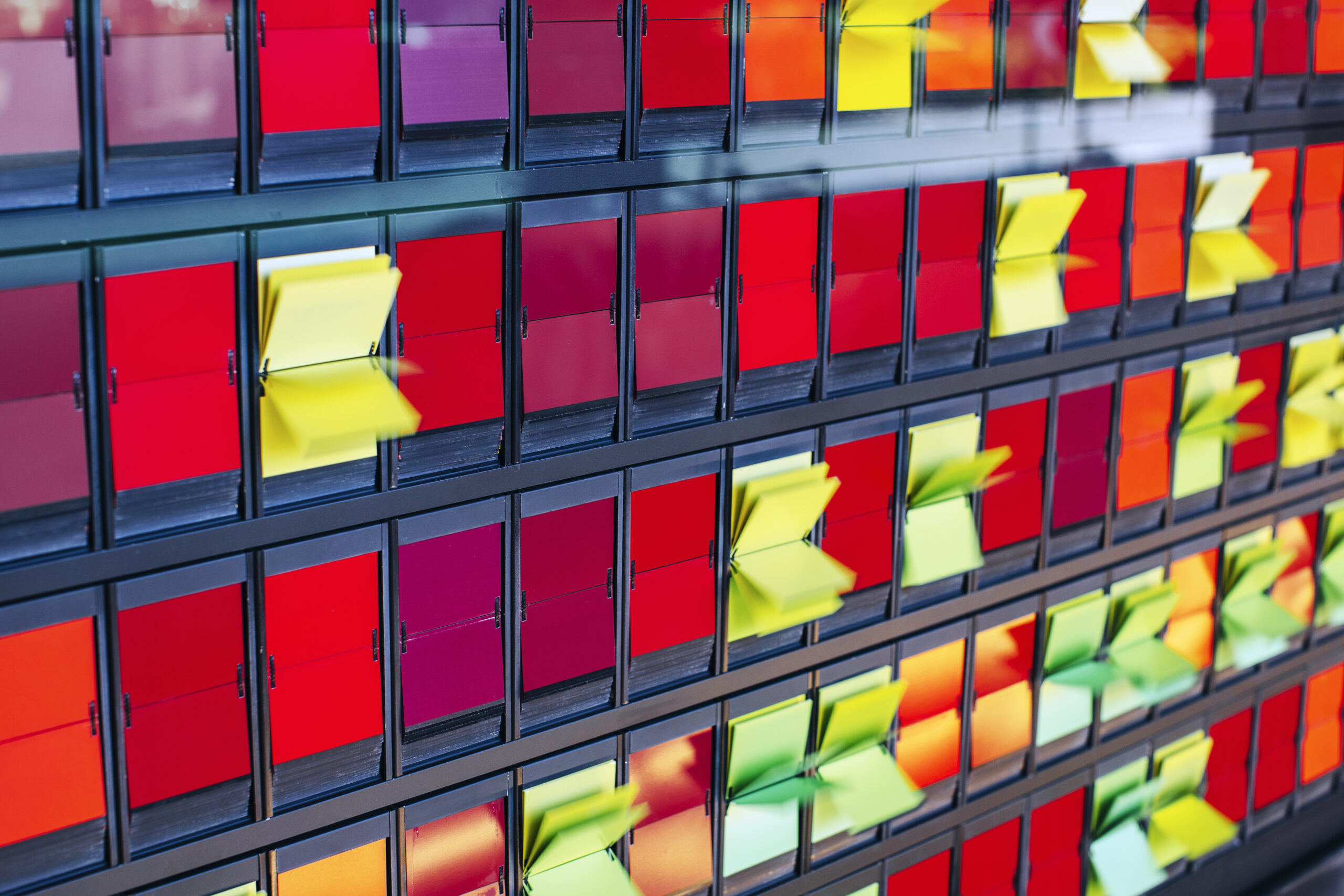 A wall installation of colored flaps programmed to produce continuous patterns of ebbing and flowing color