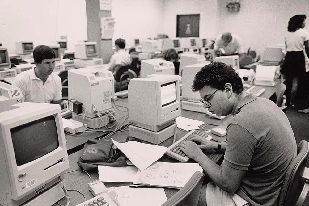 Historical black and white image from the GSB archives, showing someone working in a computer lab.
